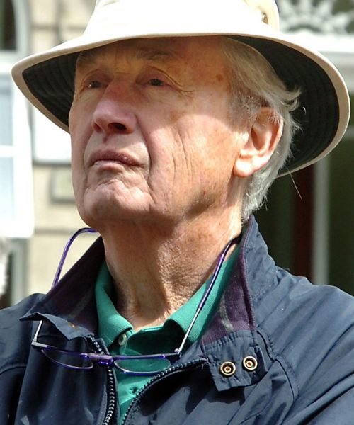 Frank McCourt wearing a sun hat and glasses around his neck, looking thoughtful.